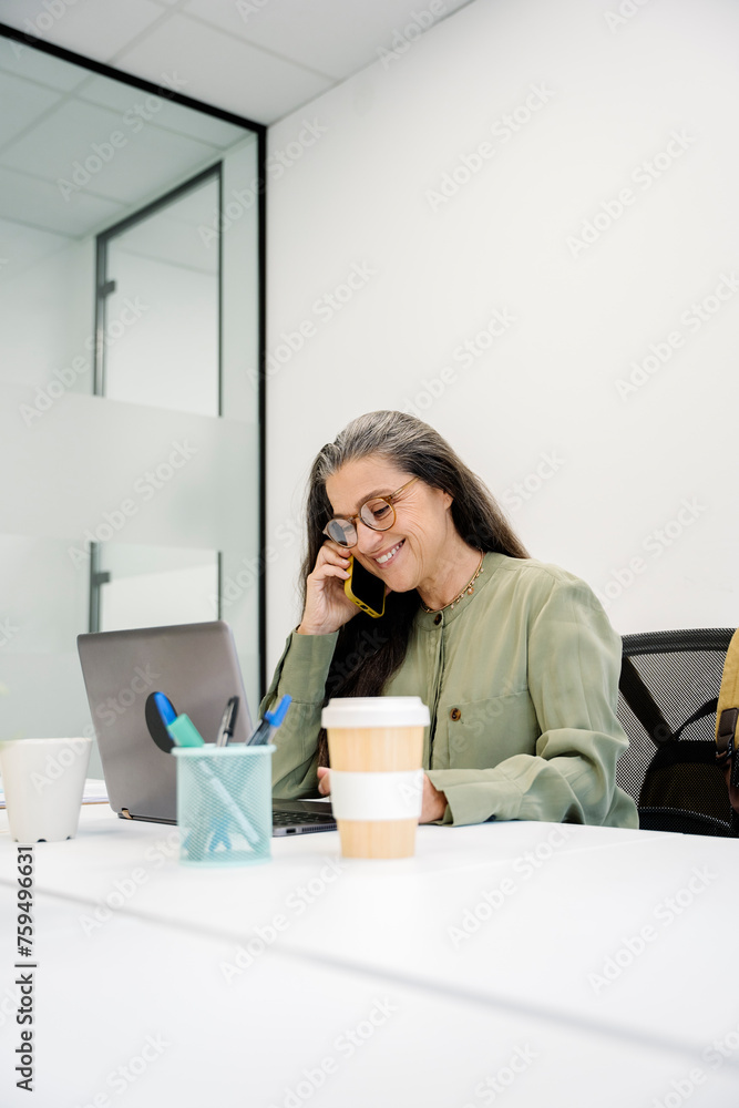 Business woman Using Laptop And Cellphone In Office Business woman Using Laptop And Cellphone In Office