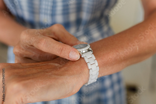 A woman adjusting the time on the wrist watch photo