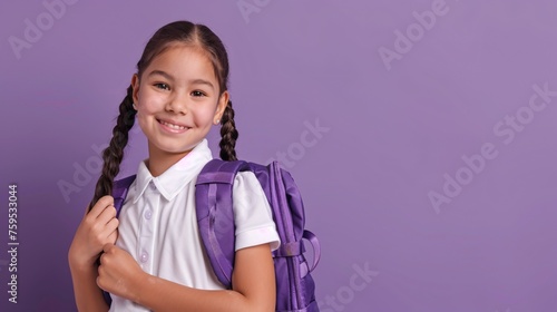 Joyful young asian preteen female Latin child pupil with pigtails in school attire holding bag standing alone on pale purple backdrop gazing into lens representing return to education idea headshot.