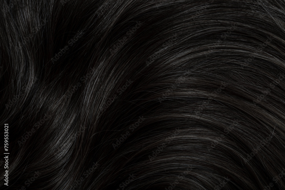 Fototapeta premium Brunette or black hair. Female long dark hair in black. Beautifully laid curls. Closeup texture in a dark key. Hairdressing, hair care and coloring. Shading gray hair. Background with copy space.