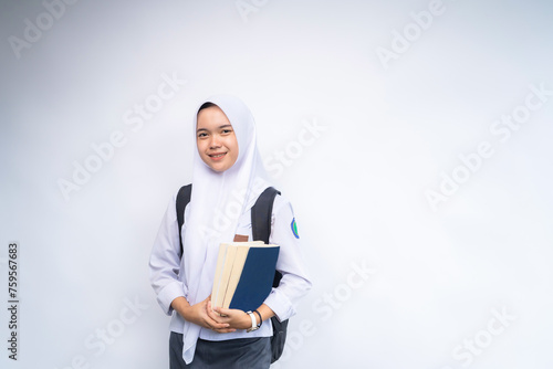 Female Indonesian high school student in white and grey uniform holding a book at Copy Space Advertising Your Text, Standing Isolated Over white Studio Background