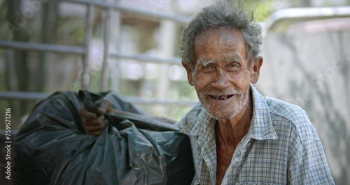 A smiling Asian man who is an elderly ragpicker or has a career collecting garbage and selling it, live in a slum village photo