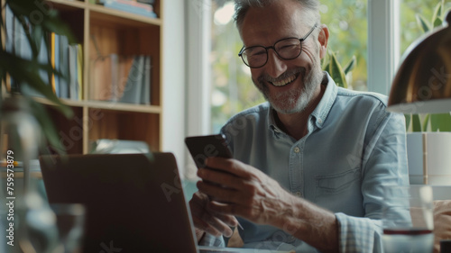 Joyful senior man with glasses engaging with technology on his smartphone.