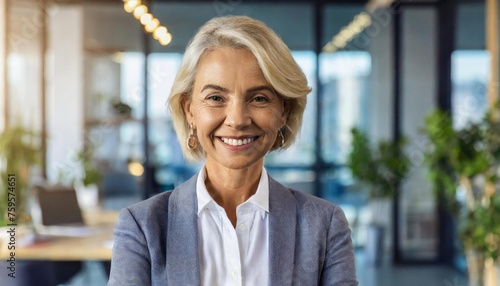 A mature businesswoman stands with self-assurance in her office space. Her bright smile reflects inner strength and empowerment, symbolizing resilience and success in the corporate world.
 photo