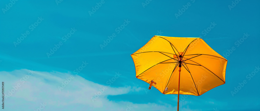 A yellow umbrella against a blue sky with a pole