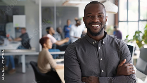 Confident businessman in a modern office environment, smiling with a team in the background.