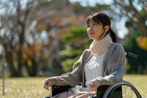 Portrait of a young disabled japanese woman sitting in a wheelchair in the park