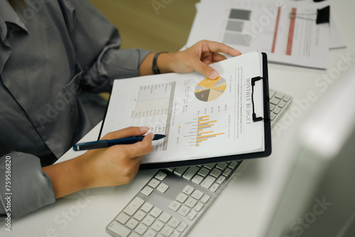 Unrecognizable female investor analyzing a documents with charts and graphs at her workplace