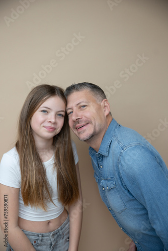 proud daddy, father is posing with his daughter in front of brown background