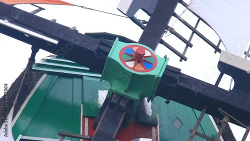 Plano cerrado del anillo giratorio adornado con pintura de diversos colores que soporta las aspas girando de un molino de viento holandés centenario en Zaanza Schans, Holanda. photo