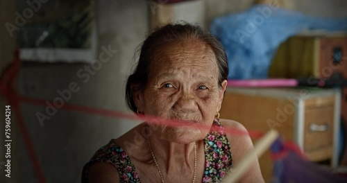 Asian woman who is elderly ragpicker's wife , while swinging a cradle to care for their infant grandchild, live in a slum village. photo