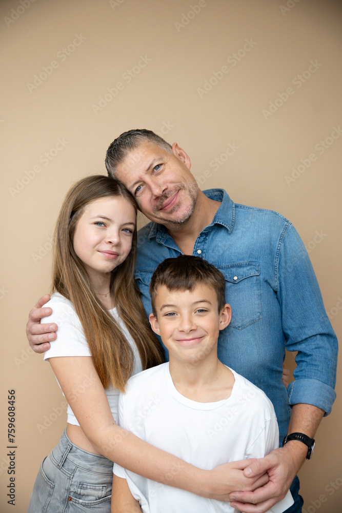 proud father with his son and his daughter posing in front of brown background
