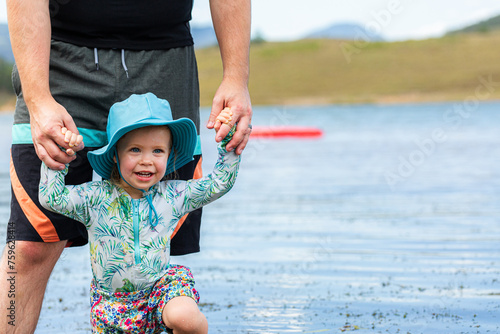 Man playing with his daughter in lake in summertime photo