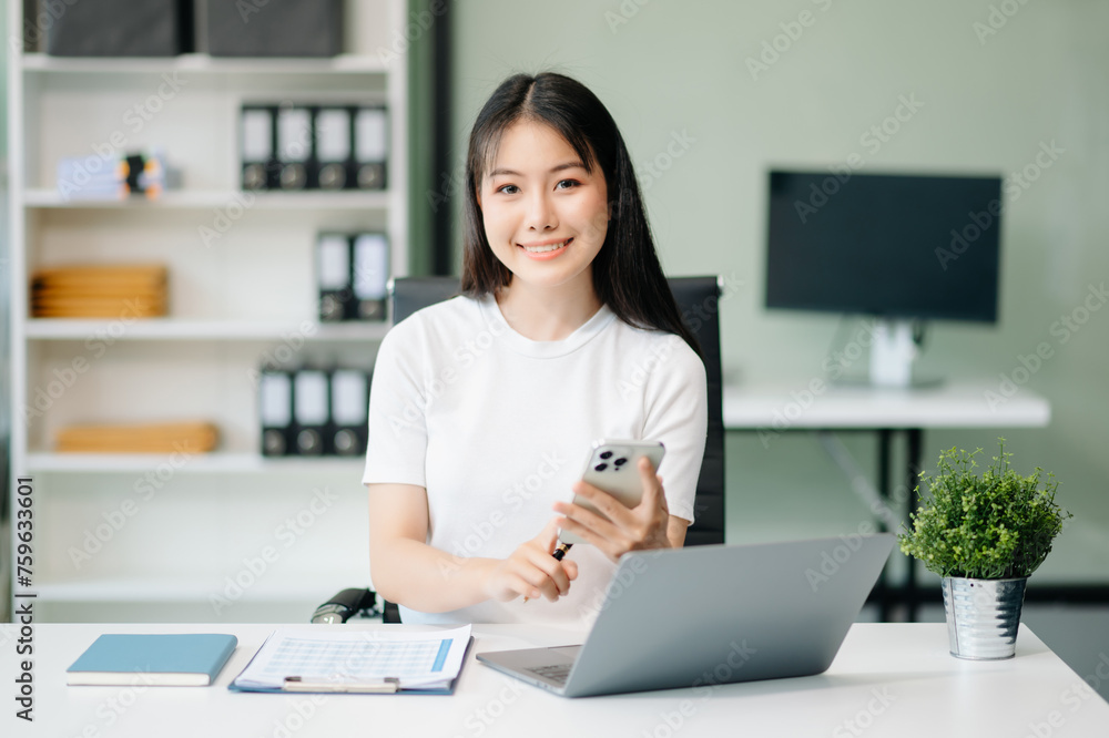 Confident Asian woman with a smile standing holding notepad and tablet at office.. Confident Asian woman with a smile standing holding notepad and tablet at office..