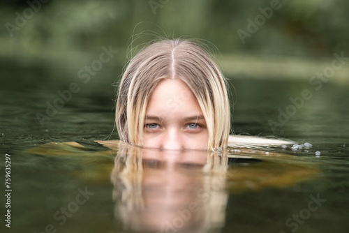 Fototapeta Naklejka Na Ścianę i Meble -  Portrait of a young beautiful blonde girl by the river.