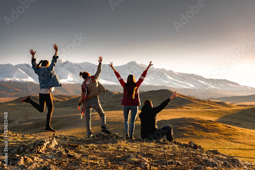Four happy tourists without backpacks are enjoying sunset in mountains