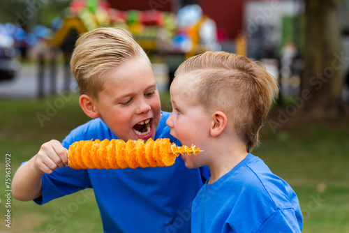 brothers sharing hot flavoured chips on a stick – Potato Spirals to eat photo