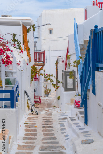 narrow side street with traditional whitewashed walls and blue accents in Mykanos Greece. traditional windmill on the sea shore and colorful restaurants © Birol