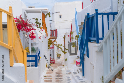 narrow side street with traditional whitewashed walls and blue accents in Mykanos Greece. traditional windmill on the sea shore and colorful restaurants © Birol