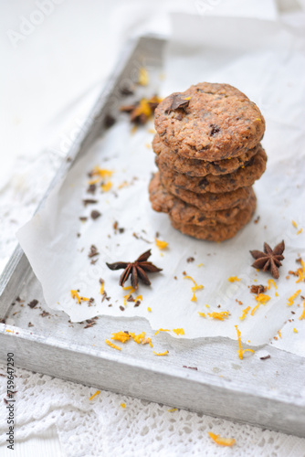 home made chocolate cookies with orange zest, chocolate chips and spices perfect for christmas on grey wooden background close up selective focus