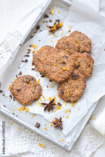 home made chocolate cookies with orange zest, chocolate chips and spices perfect for christmas on grey wooden background close up selective focus