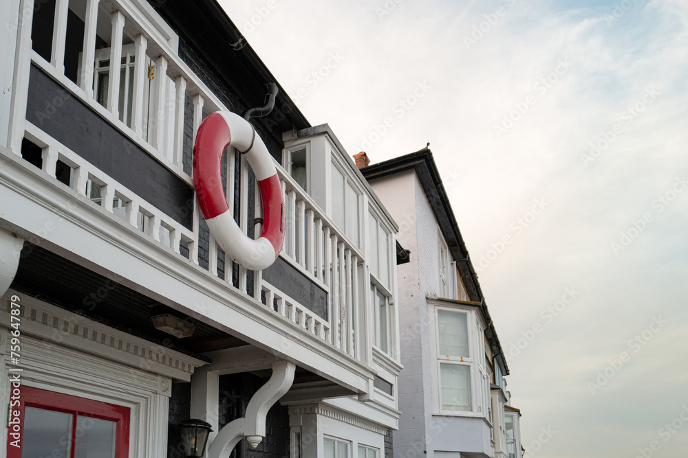 Obraz premium Life ring seen hanging from a balcony of a town house overlooking the Suffolk North Sea. Houses are used as holiday lets in the summer season.