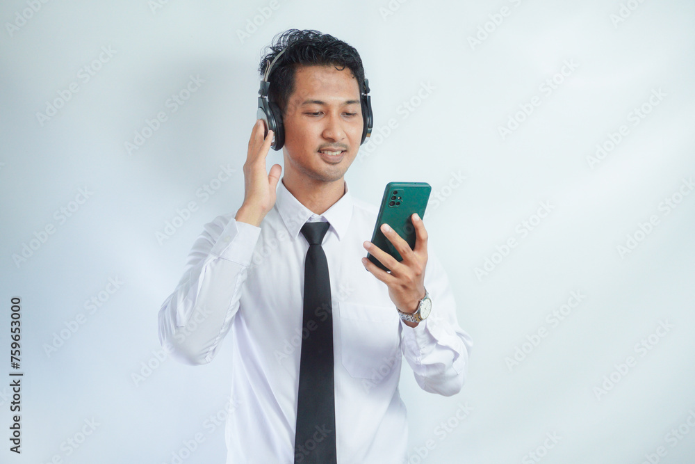 Asian man enjoying music from mobile phone using wireless headset isolated on white Asian man enjoying music from mobile phone using wireless headset isolated on white