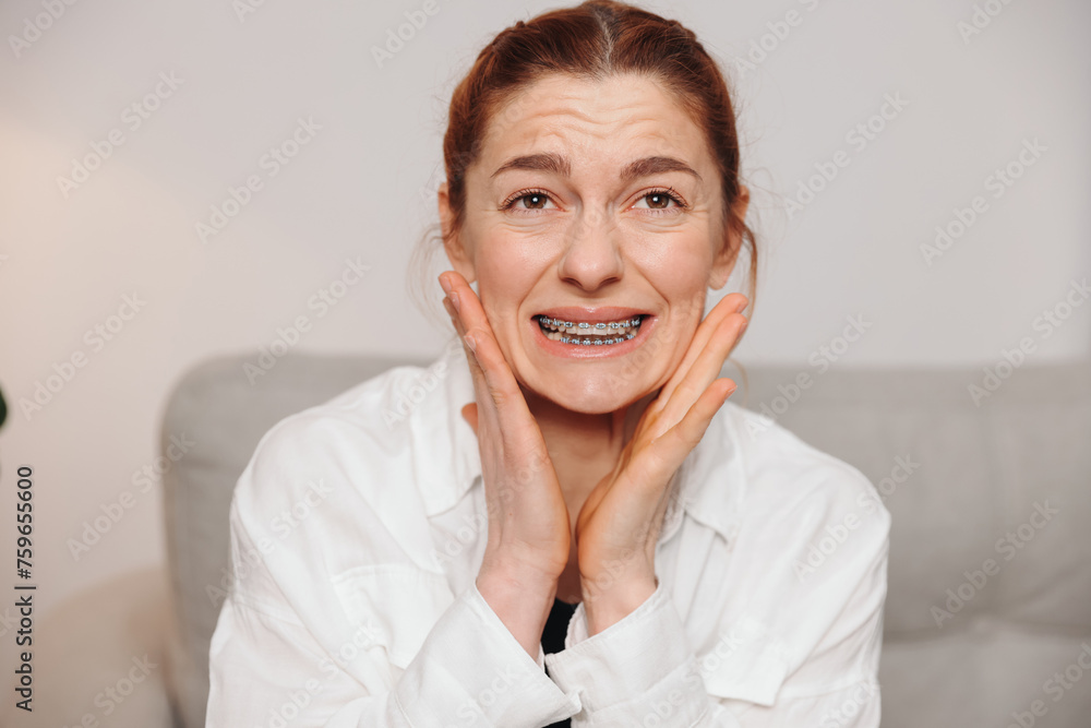 Portrait of red-haired mature woman suffering from pain due to braces Portrait of red-haired mature woman suffering from pain due to braces