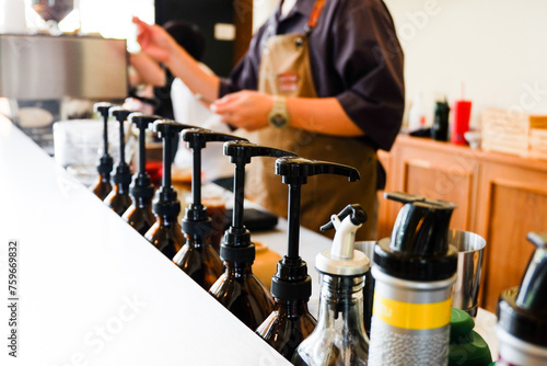 Row of pump head bottle of beverage in the cafe,Pump at the head of bottles for caramel, syrup and smell addition for coffee in cafe,Space for text,closeup concept.