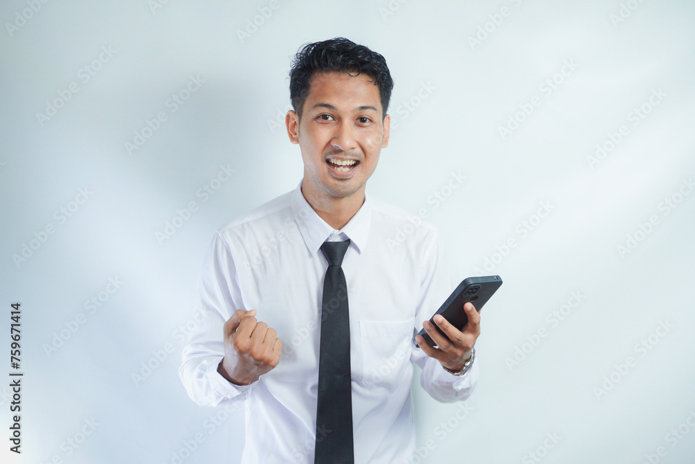 Adult Asian man looking camera while holding mobile phone showing enthusiastic expression Adult Asian man looking camera while holding mobile phone showing enthusiastic expression
