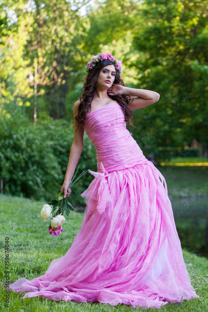Glamorous healthy woman with makeup and long wavy dark brown hairstyle with flowers on head in spring park outdoor Glamorous healthy woman with makeup and long wavy dark brown hairstyle with flowers on head in spring park outdoor