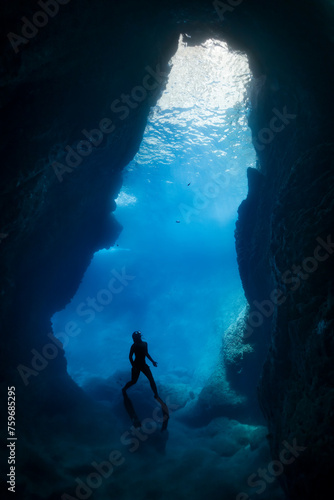silhouette of free diver woman freediving in cave.