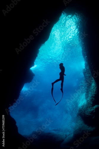 silhouette of free diver woman freediving in cave.