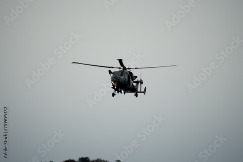 British army AgustaWestland AW159 Wildcat AH1 helicopter flying low over open countryside