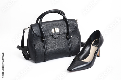 Black women's leather bag and a pair of black high-heeled shoes on a white background