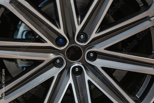 A close up of a car wheel with a sleek black and silver alloy rim, showcasing modern automotive design. The tire tread made of synthetic rubber adds to the overall aesthetic of the vehicle