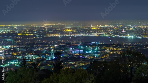 Night timelapse top overview of besiktas district with traffic in istanbul taken from asian part of the city on Camlica hill. Reflection on Bosphorus water with floaing ship photo