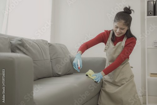 Asian woman doing housework wearing an apron cleaning the wooden floor in the living room Happy housewife doing housework at home with attractive smile, house cleaning concept