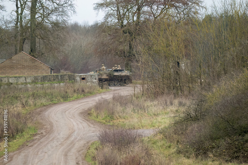 soldiers atop a British army FV432 Bulldog APC moving in to a wall protected village © Martin