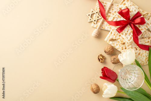 Upscale Passover scheme, top view shot of ribboned matza, wine goblet, nuts, star of David, honey spoon, and tulips against a pastel beige setting, empty slot for text