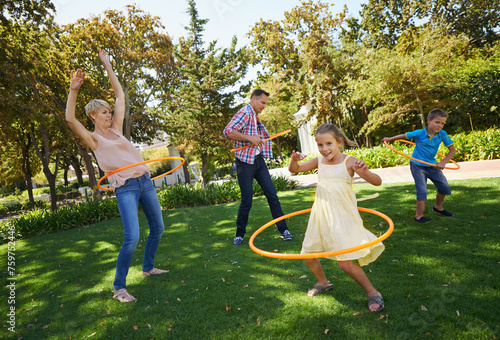 Parents, kids and hula hoop in park for playing, child development and motor skills outdoor. Children, son and daughter with mom and dad in nature for leisure, family time and bonding with smile photo