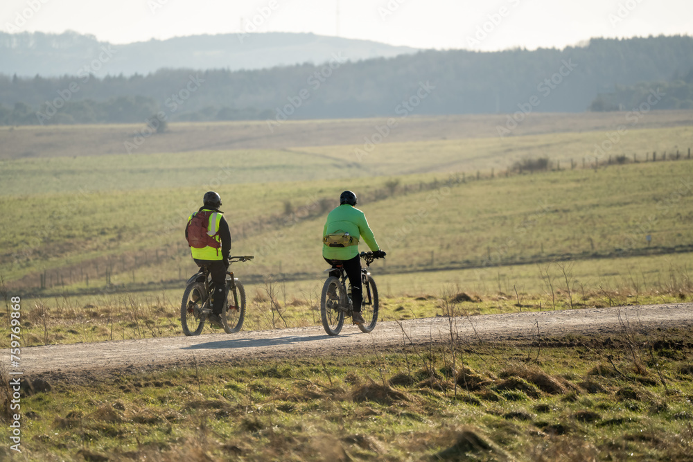 a pair of casual cyclists in high-vis jackets on a stone track crossing salisbury plain, Wiltshire UK