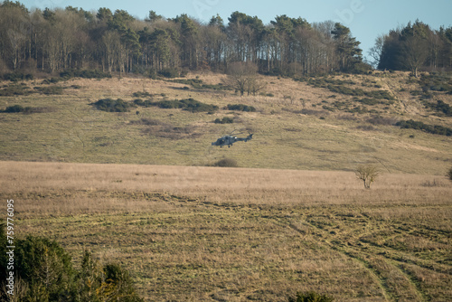 British army AgustaWestland AW159 Wildcat AH1 helicopter in low level flight over countryside