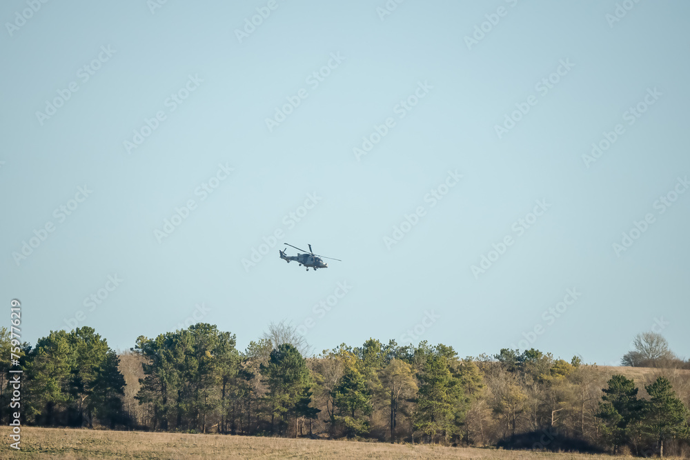 British army AgustaWestland AW159 Wildcat AH1 helicopter in low level flight over countryside British army AgustaWestland AW159 Wildcat AH1 helicopter in low level flight over countryside
