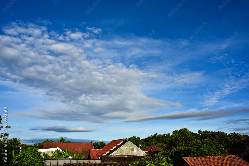 Beautiful cloudy blue morning sky with houses roof foreground at bottom Beautiful cloudy blue morning sky with houses roof foreground at bottom