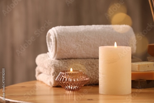 Spa composition. Burning candles, towels and soap on wooden table, space for text