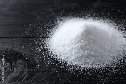 Pile of organic salt on black wooden table, closeup. Space for text