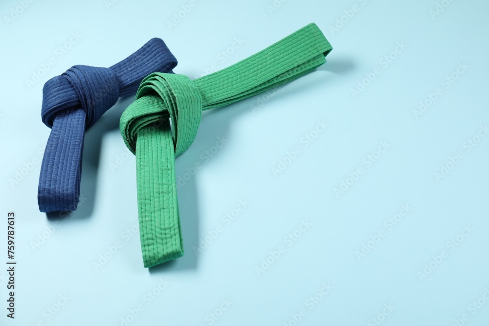 Colorful karate belts on light blue background, space for text Colorful karate belts on light blue background, space for text