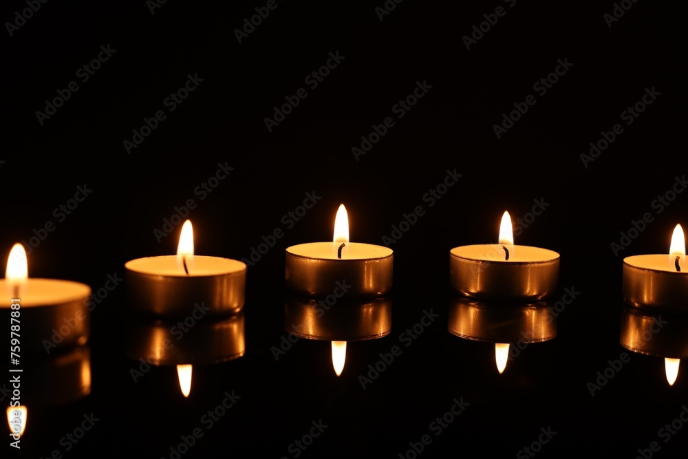 Burning candles on mirror surface in darkness Burning candles on mirror surface in darkness