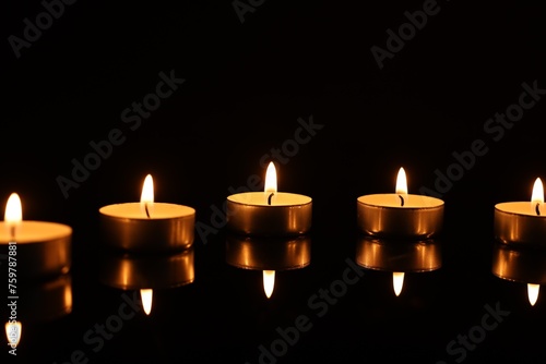 Burning candles on mirror surface in darkness